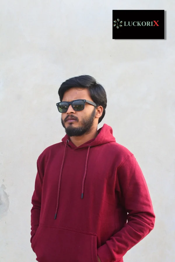 A man wearing a maroon hoodie with sunglasses, posing confidently against a neutral wall. The LuckoriX logo is displayed in the top right corner.