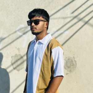 "Stylish young man wearing a modern dual-tone polo shirt from LuckoriX, standing against a sunlit concrete wall"