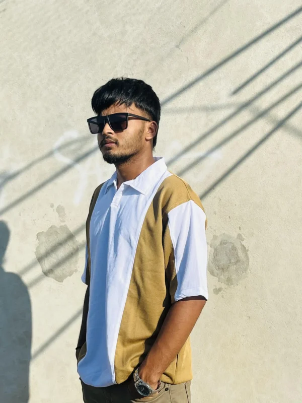 "Stylish young man wearing a modern dual-tone polo shirt from LuckoriX, standing against a sunlit concrete wall"