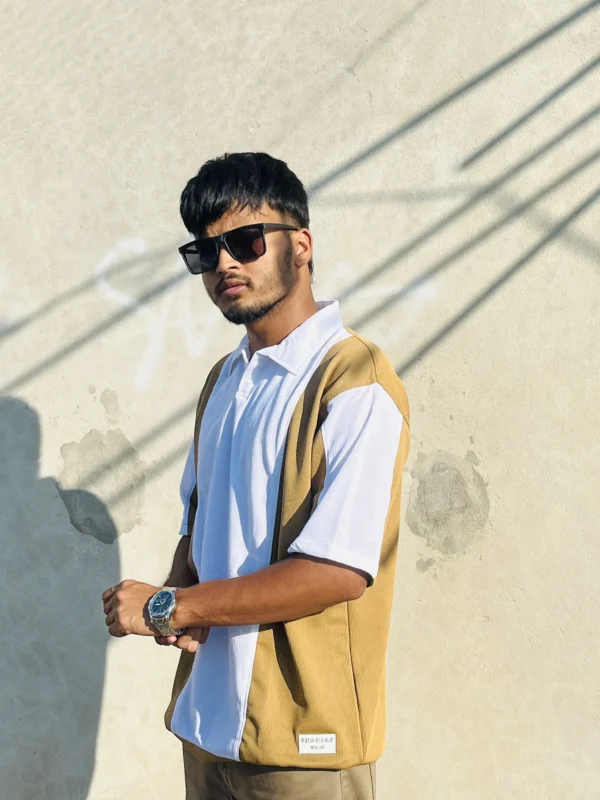 Male model wearing LuckoriX mustard and white color-block polo shirt in bright sunlight against a concrete wall